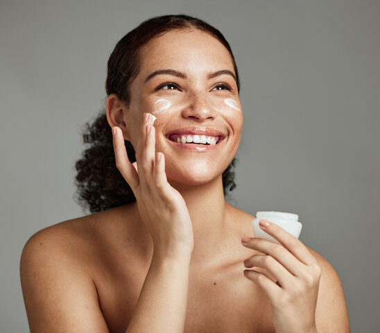 Woman applying cream to her face - Semper Amate Skin Care 